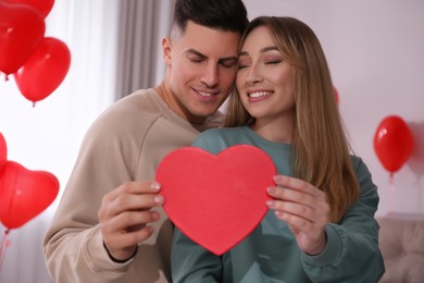 Photo of Lovely couple with gift in room. Valentine's day celebration