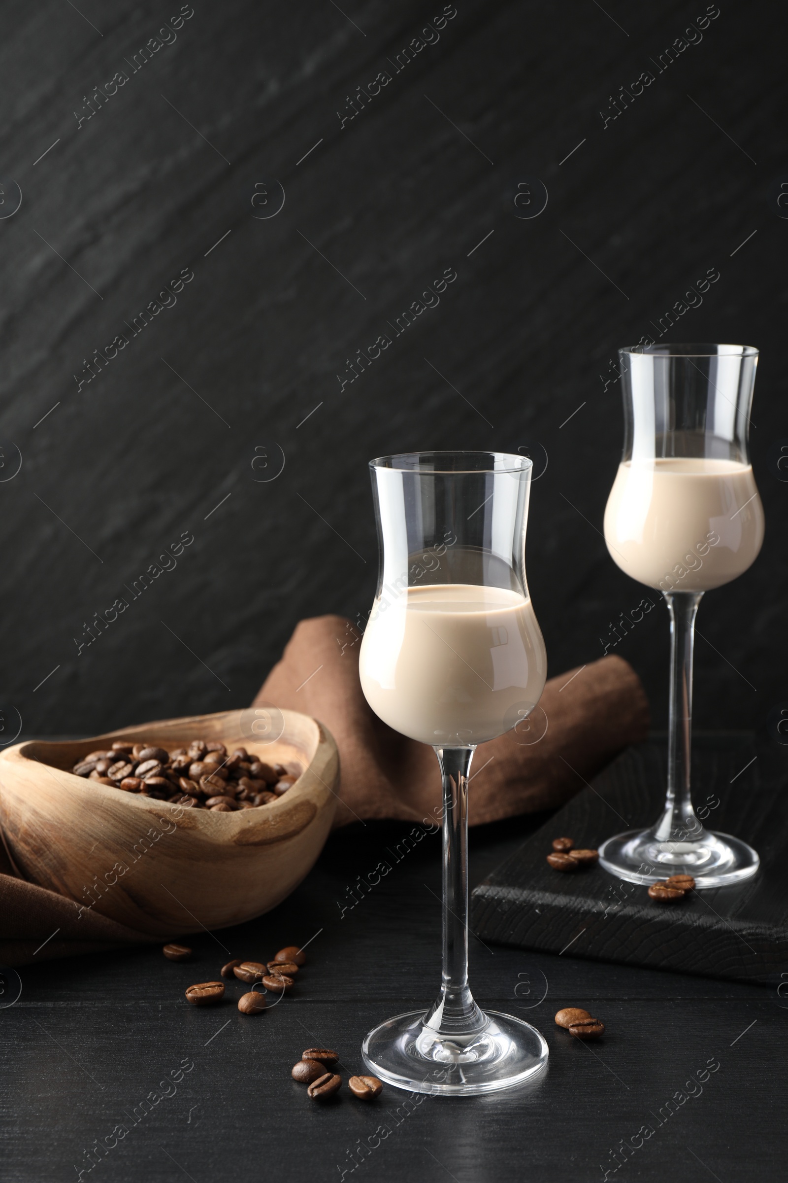Photo of Coffee cream liqueur in glasses and beans on black wooden table