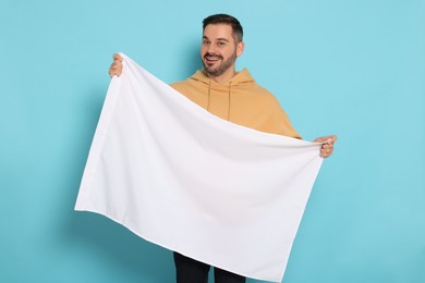Photo of Man with blank white flag on light blue background. Mockup for design