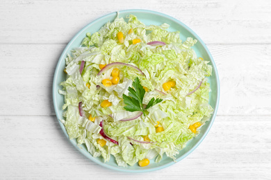 Photo of Fresh napa cabbage salad served on white wooden table, top view