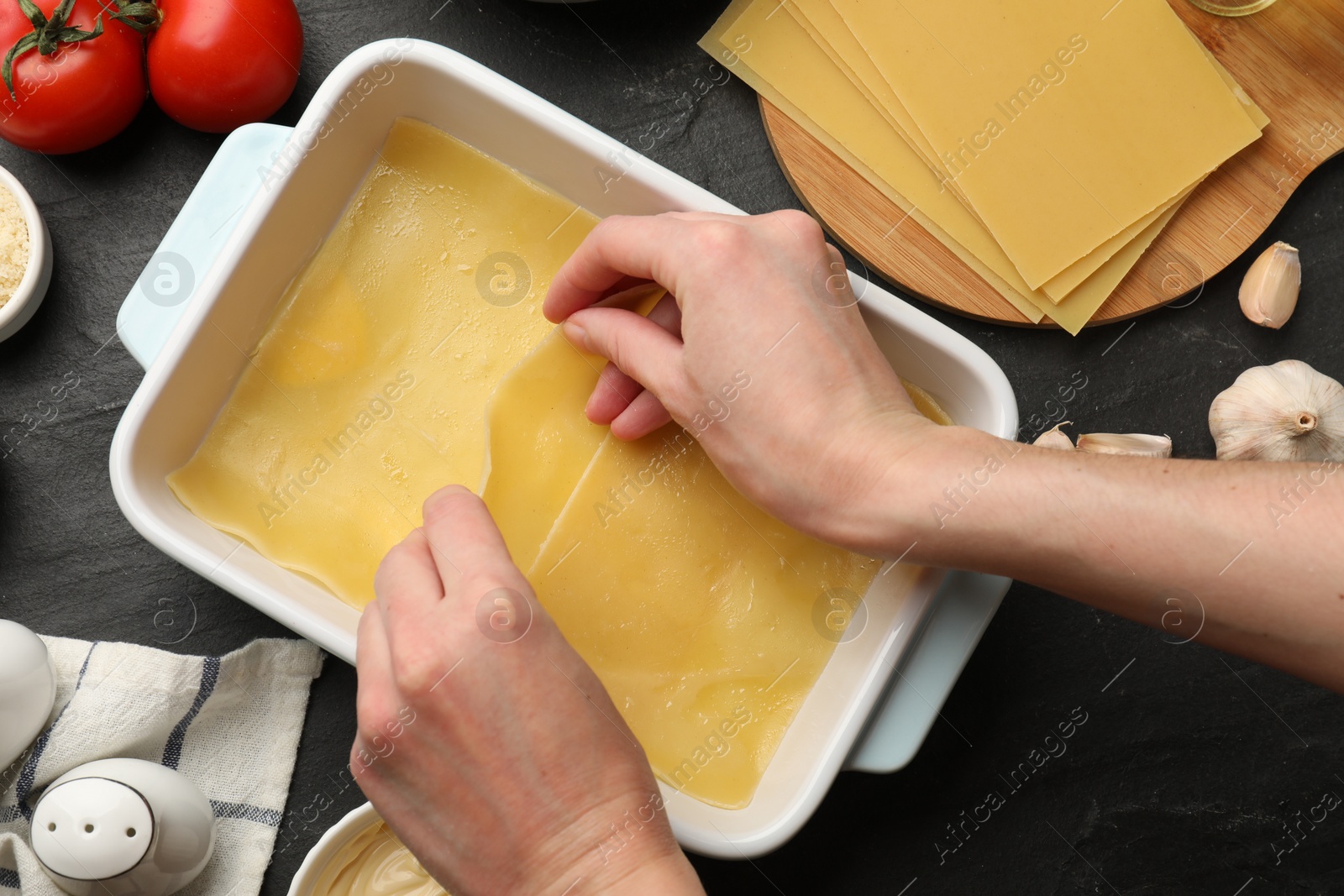 Photo of Woman making lasagna at dark table, top view