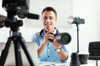 Photo of Male photo blogger recording video on camera indoors