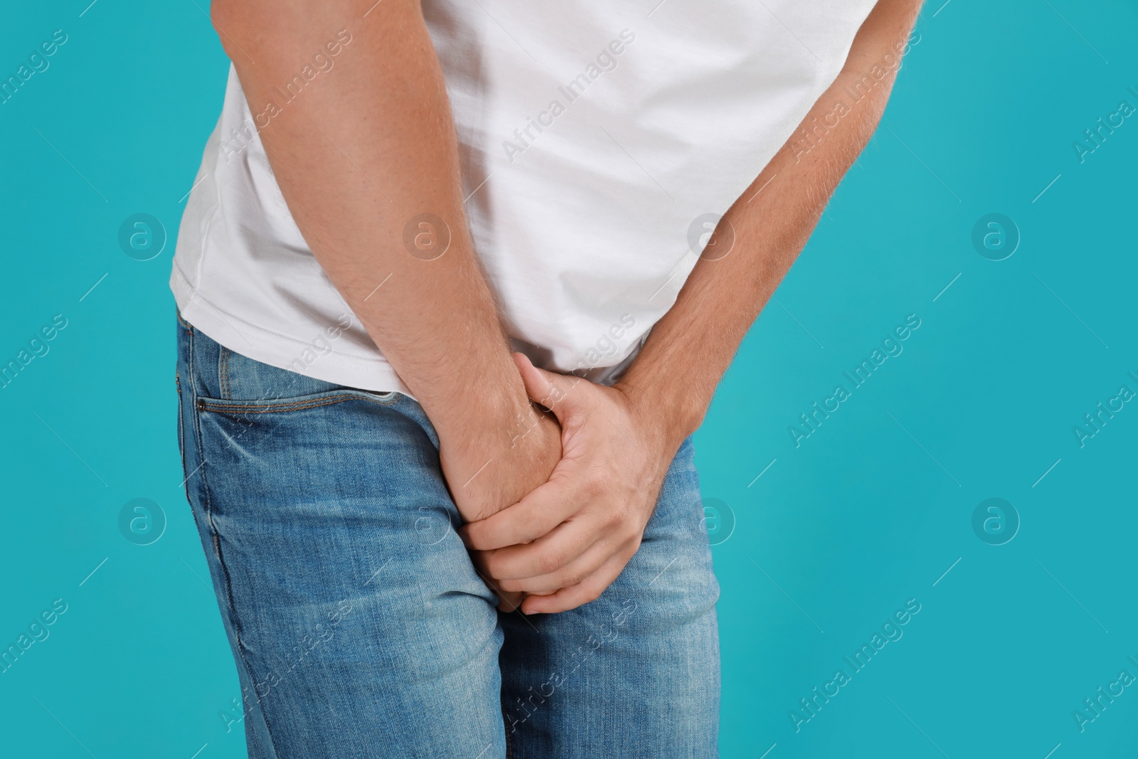 Photo of Man suffering from pain on turquoise background, closeup. Urology problems