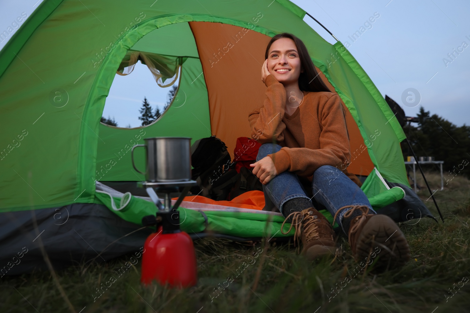 Photo of Happy young woman in camping tent outdoors