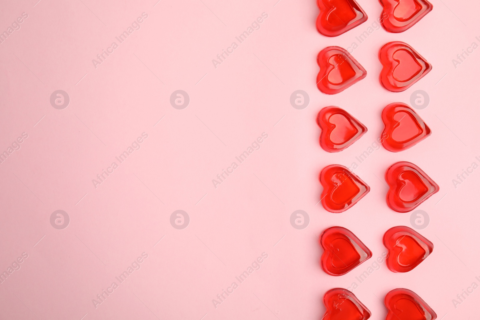 Photo of Sweet heart shaped jelly candies on pink background, flat lay. Space for text