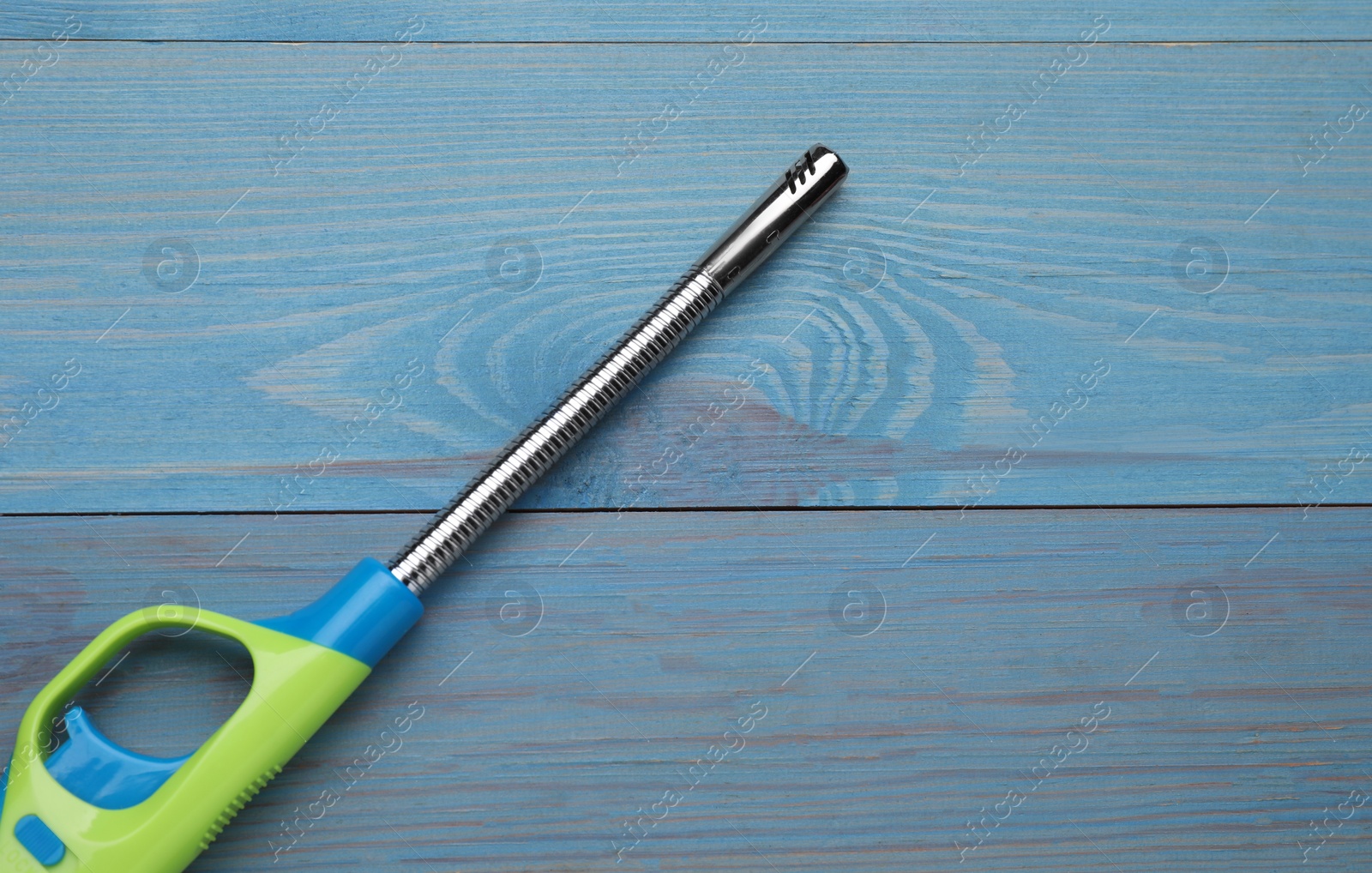 Photo of One gas lighter on light blue wooden table, top view. Space for text