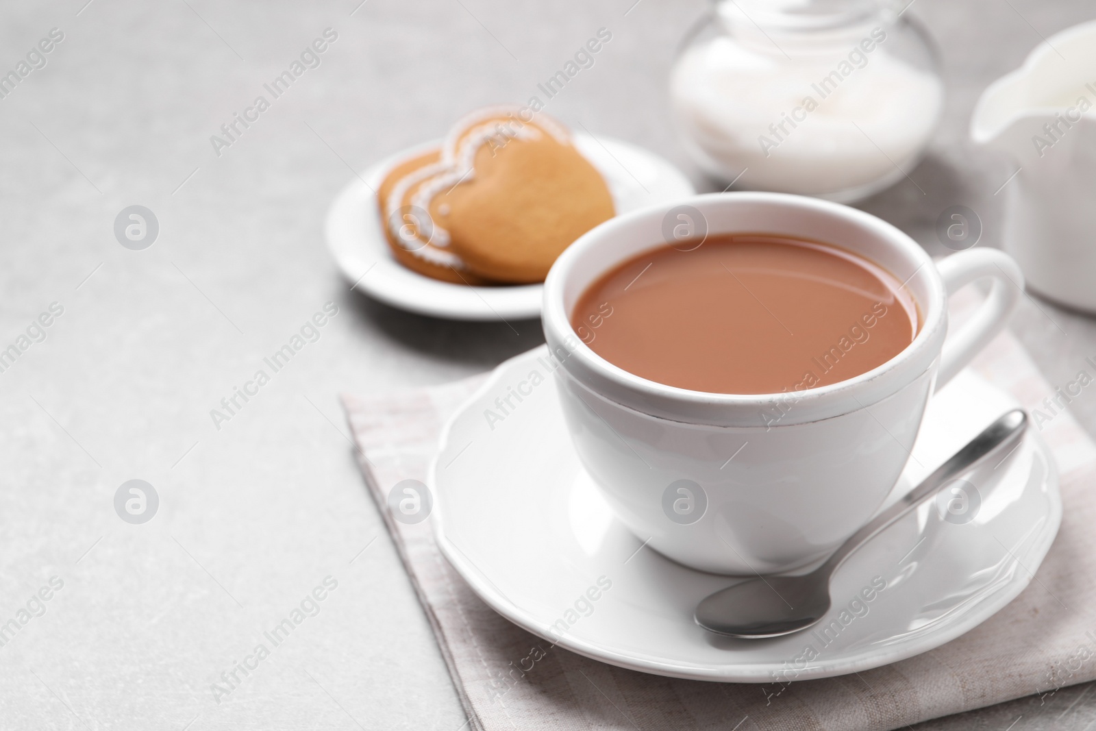 Photo of Delicious tea with milk in white cup near cookies on grey table, space for text