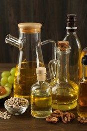 Photo of Vegetable fats. Different oils in glass bottles and ingredients on wooden table, closeup