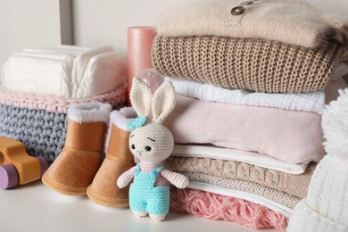 Photo of Baby clothes, toy and accessories on white table