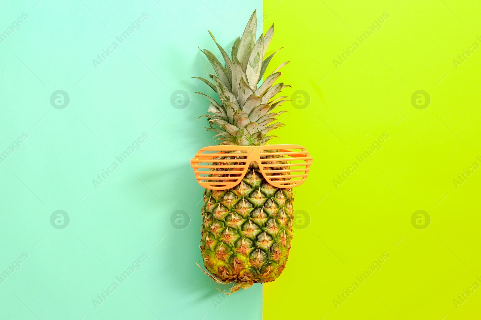 Photo of Fresh ripe pineapple with sunglasses on color background, top view