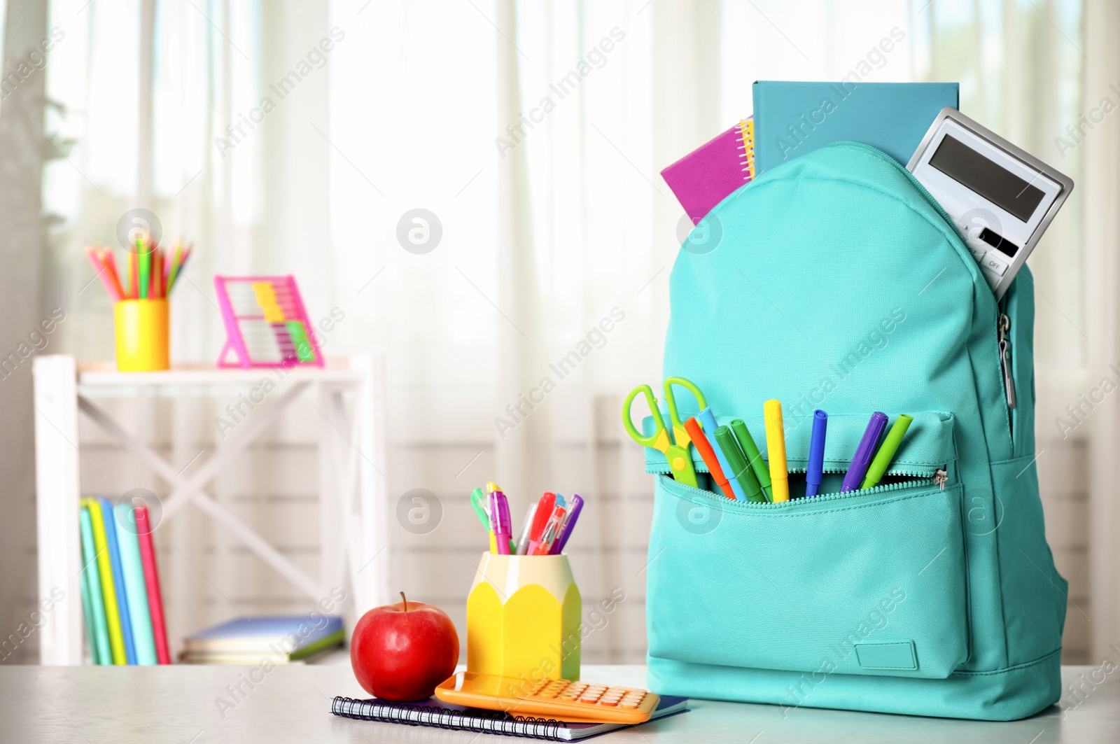 Photo of Bright backpack and school stationery on table indoors, space for text