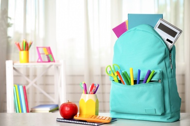 Photo of Bright backpack and school stationery on table indoors, space for text