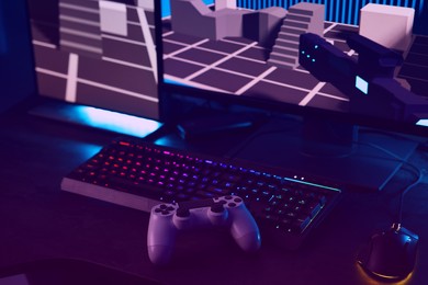 Photo of Playing video games. Computer monitor, keyboard, mouse and wireless controller on table indoors