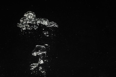 Air bubbles in water on black background, space for text