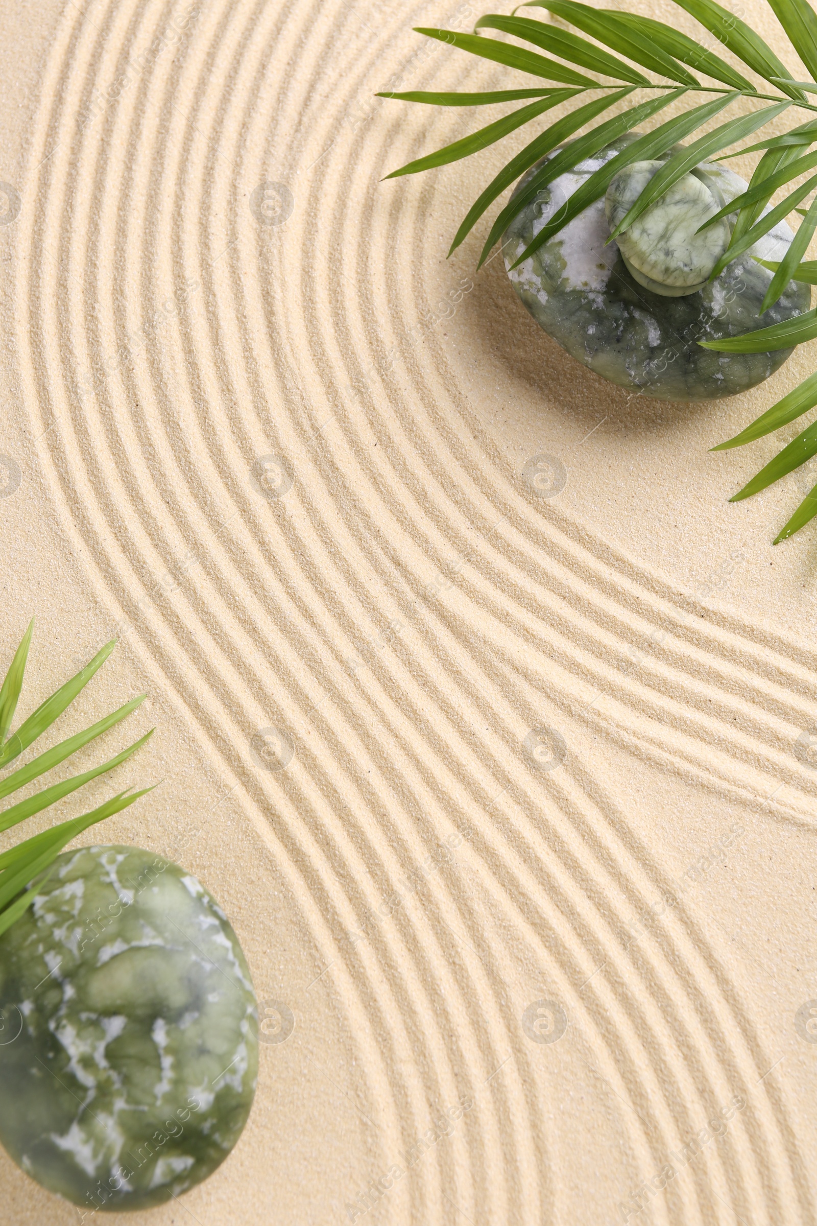 Photo of Zen concept. Stones, leaves and pattern on beige sand, flat lay. Space for text