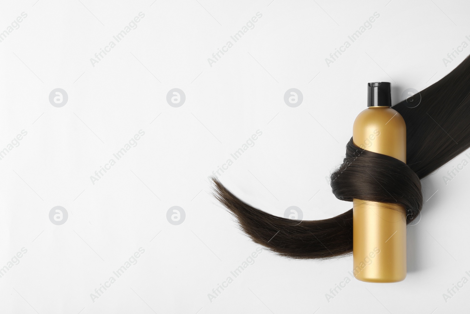 Photo of Shampoo bottle wrapped in lock of hair isolated on white, top view. Natural cosmetic products