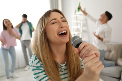 Young woman singing karaoke with friends at home
