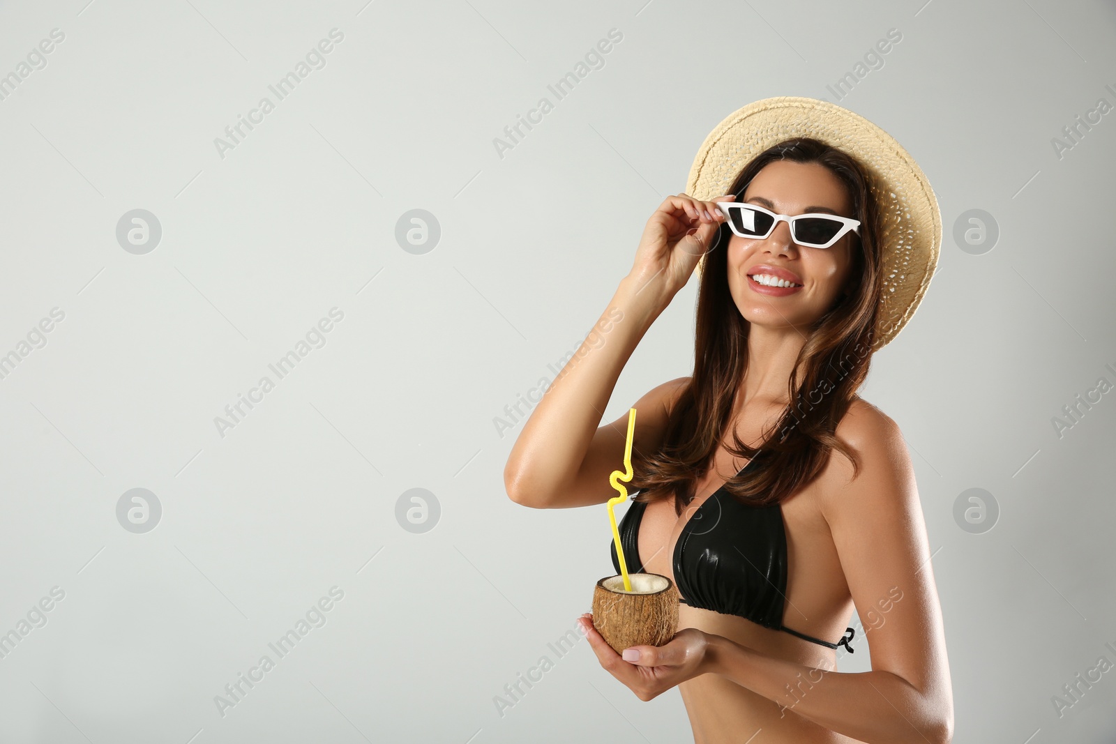 Photo of Beautiful woman in stylish bikini with tropical cocktail on light grey background. Space for text