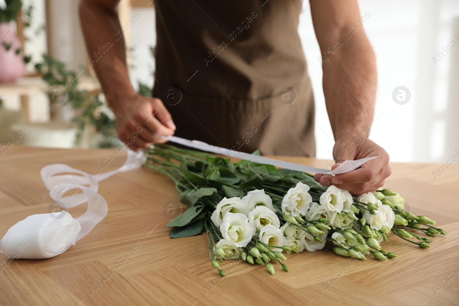 Photo of Florist making beautiful bouquet at table in workshop, closeup