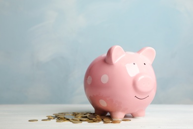 Cute piggy bank and heap of coins on table