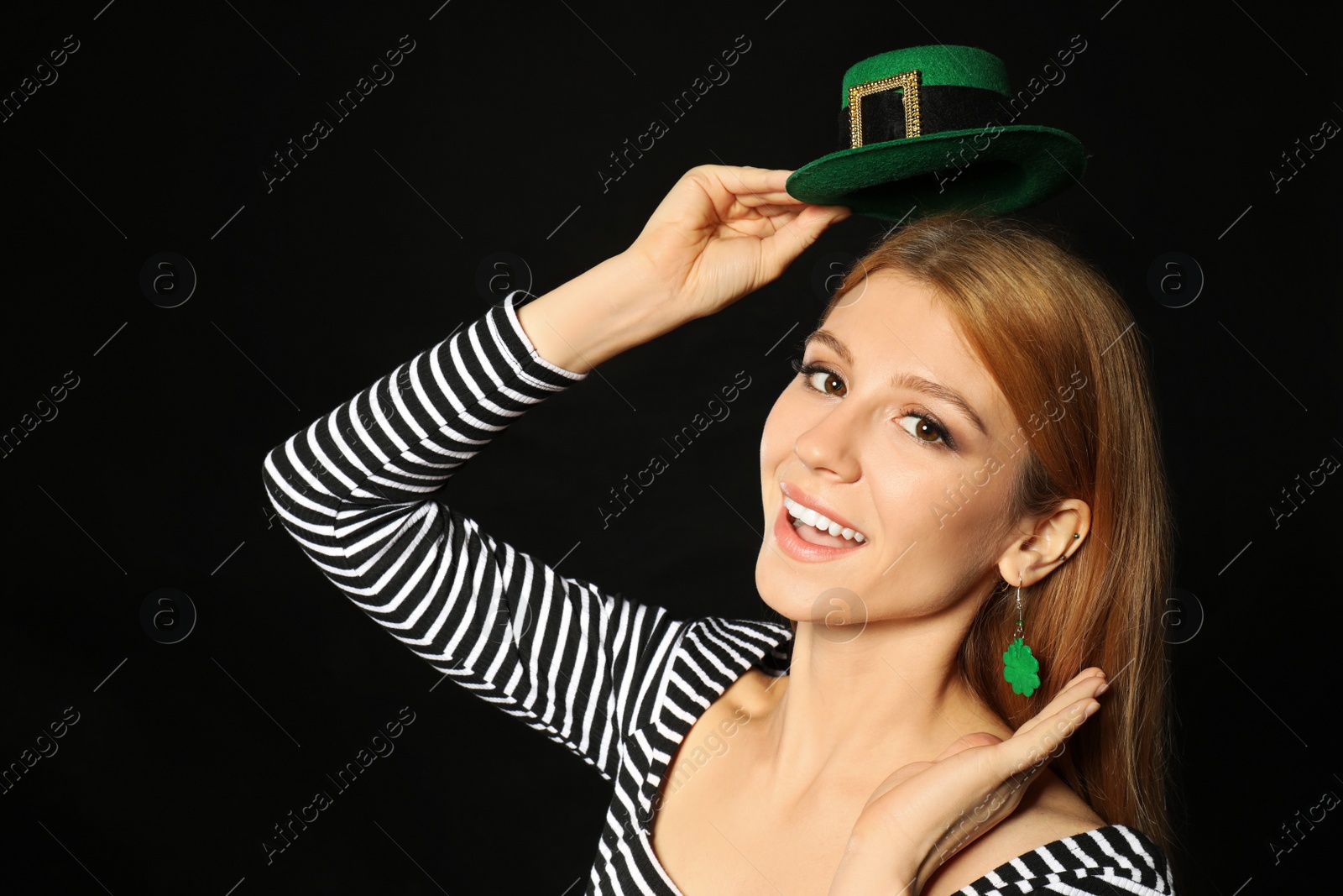 Photo of Young woman with green leprechaun hat on black background. St. Patrick's Day celebration