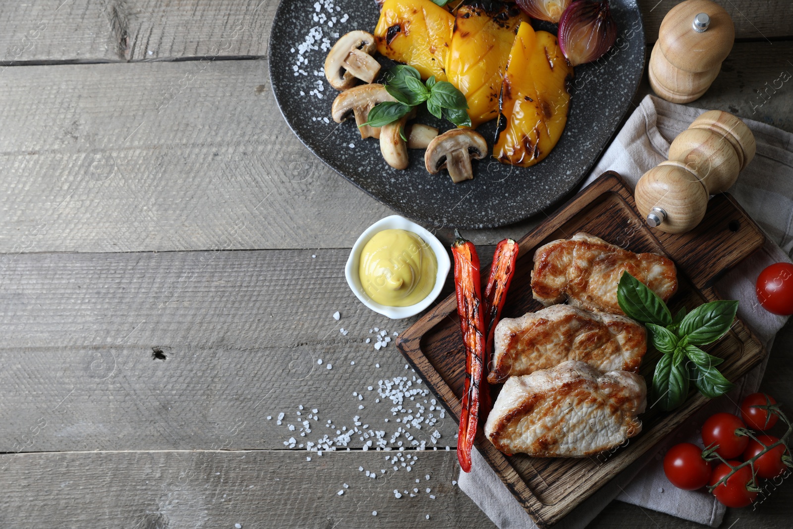 Photo of Delicious grilled meat and vegetables served on wooden table, flat lay. Space for text