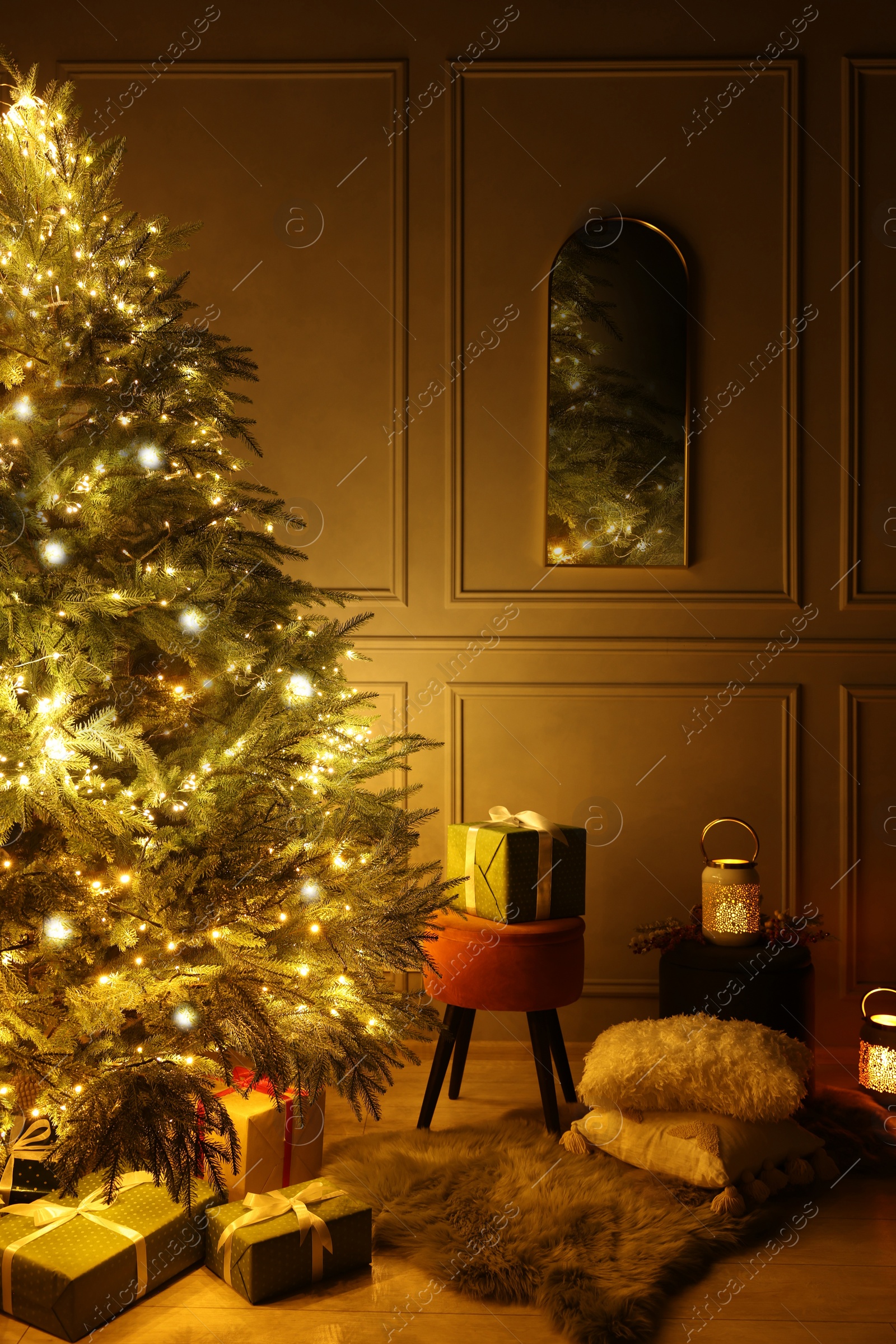 Photo of Beautiful Christmas tree decorated with festive lights and many gift boxes in room