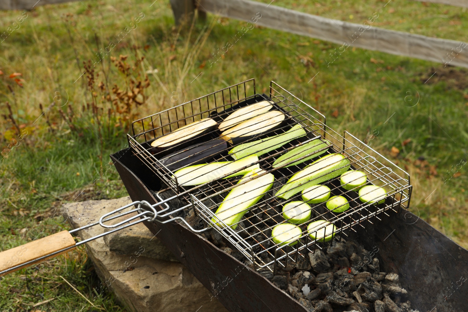 Photo of Cooking delicious zucchini on metal grid for barbecue outdoors