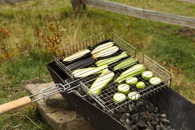 Photo of Cooking delicious zucchini on metal grid for barbecue outdoors