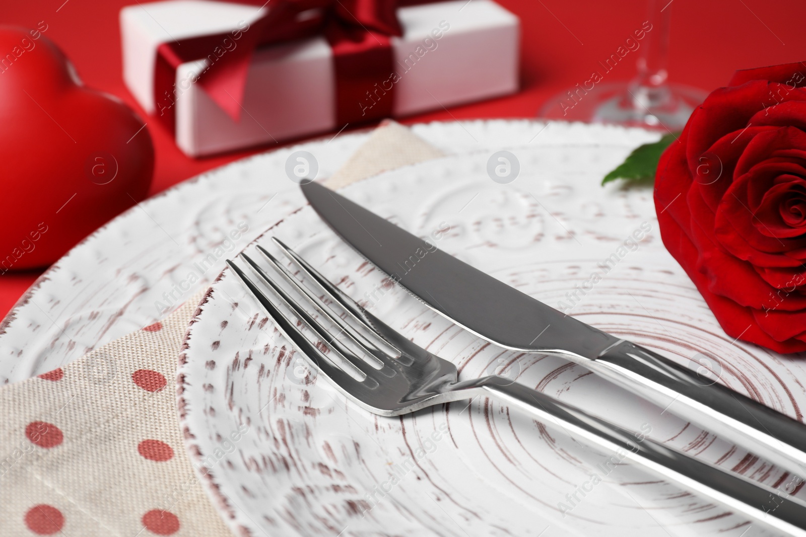 Photo of Beautiful dishware with rose and gift on table, closeup. Romantic date