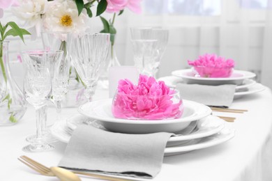 Photo of Stylish table setting with beautiful peonies in dining room, closeup