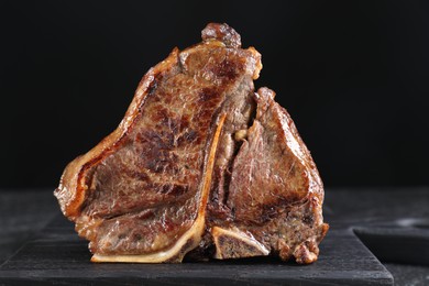 Photo of Delicious fried beef meat on table against black background
