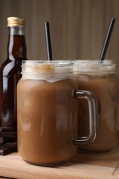 Photo of Delicious iced coffee with chocolate syrup on wooden board, closeup