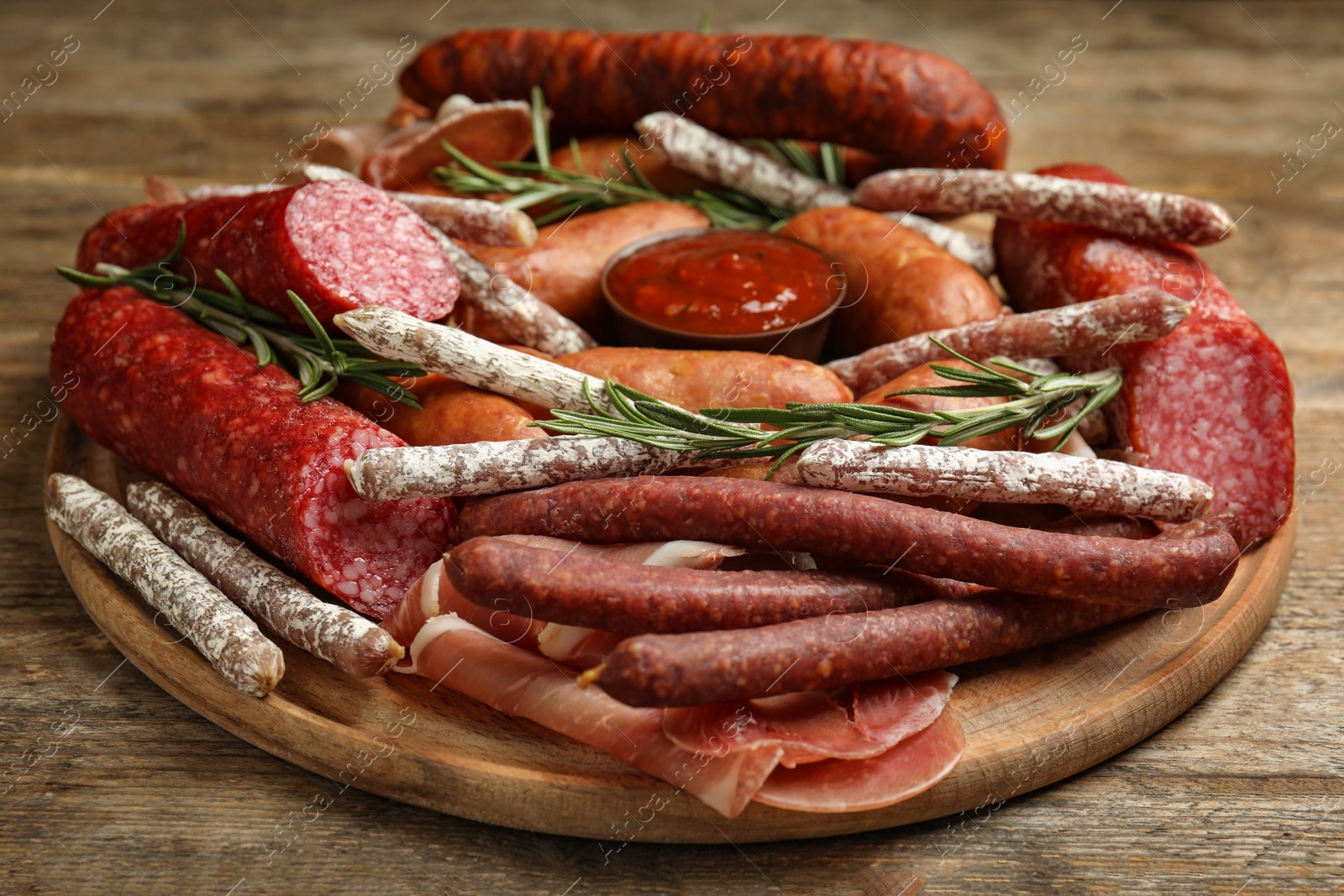 Photo of Different types of sausages with rosemary served on wooden table