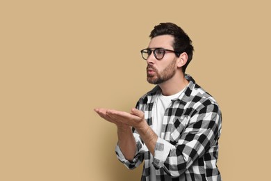 Handsome man blowing kiss on beige background. Space for text