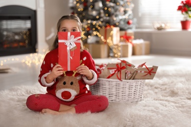 Cute little girl holding gift from Christmas advent calendar at home, space for text