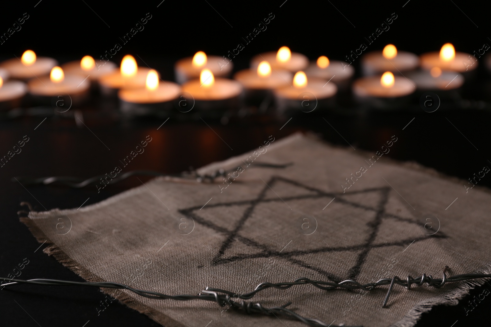 Photo of Fabric with star of David and barbed wire on black background. Holocaust memory day