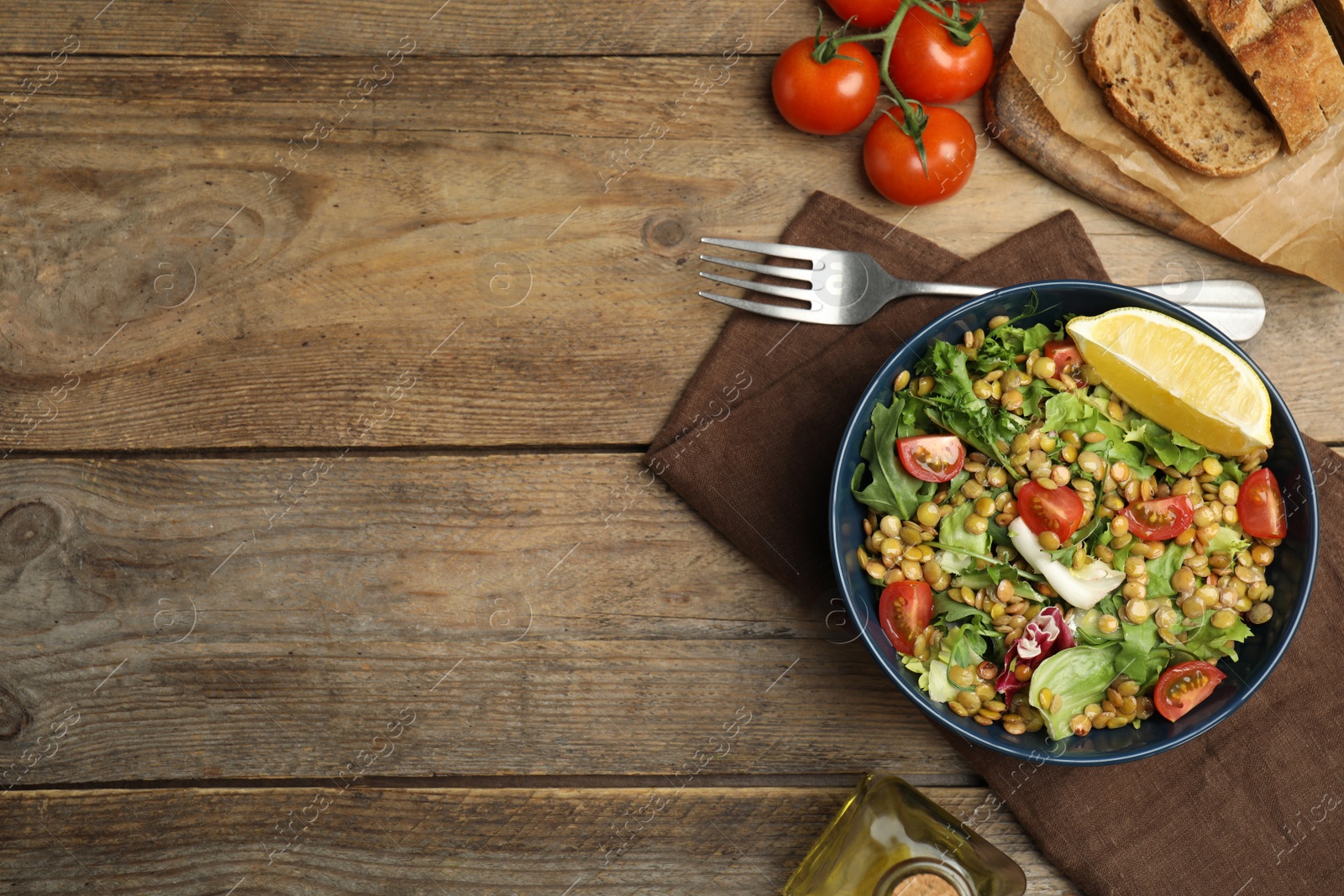 Photo of Delicious salad with lentils and vegetables served on wooden table, flat lay. Space for text