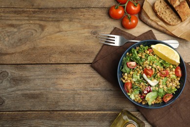 Delicious salad with lentils and vegetables served on wooden table, flat lay. Space for text