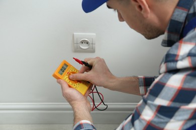 Photo of Electrician with tester checking voltage indoors, closeup