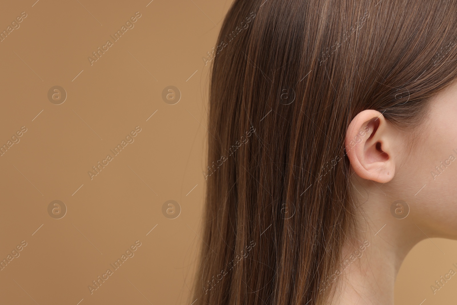Photo of Hearing problem. Little girl on pale brown background, closeup. Space for text