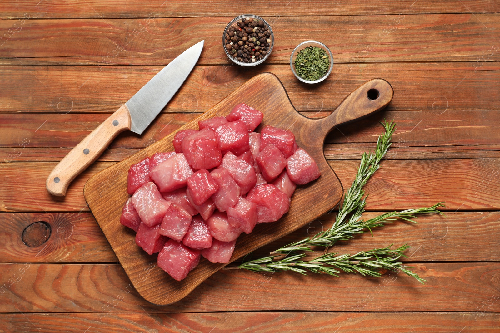 Photo of Cooking delicious goulash. Raw beef meat, knife and different spices on wooden table, flat lay