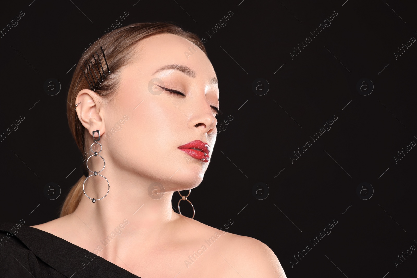 Photo of Young woman with lip and ear piercings on black background, space for text