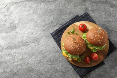 Photo of Delicious burgers with beef patty and tomatoes on grey table, top view. Space for text