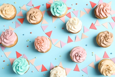 Photo of Flat lay composition with delicious birthday cupcakes on color background