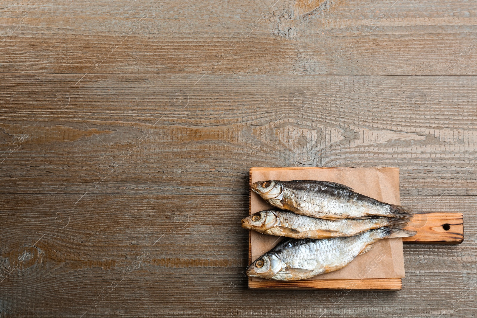 Photo of Tasty dried fish with on wooden table, top view. Space for text