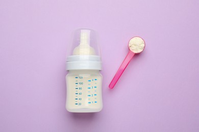 Photo of Feeding bottle with infant formula and powder on violet  background, flat lay