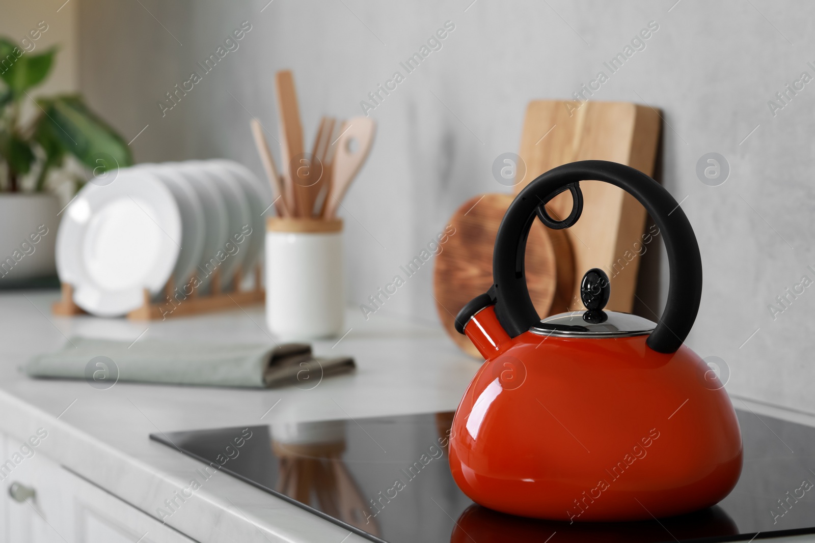 Photo of Red kettle with whistle on cooktop in kitchen. Space for text