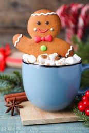 Photo of Gingerbread man in cup on blue wooden table
