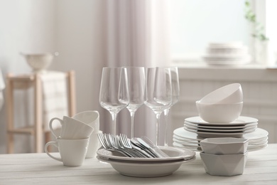 Set of clean dishware, cutlery and wineglasses on white table indoors